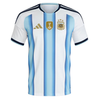 Argentina Home Football Shirt 2026 Adidas white showing sky blue gradient vertical stripe Albiceleste classic AFA Argentina Football Association crest 3 gold stars FIFA World Cup 2022 winner gold trophy badge gold Adidas 3-bar logo navy V-neck collar light blue inner accent navy Adidas 3-stripe shoulders navy light blue cuff trim front view on white background