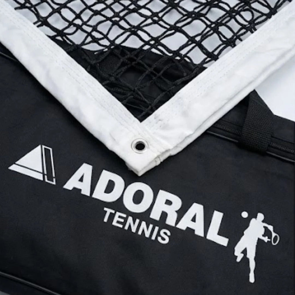 Adoral lawn tennis net double close-up showing black nylon mesh white tape border with metal eyelet and Adoral Tennis branding