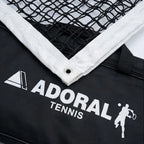 Adoral lawn tennis net double close-up showing black nylon mesh white tape border with metal eyelet and Adoral Tennis branding