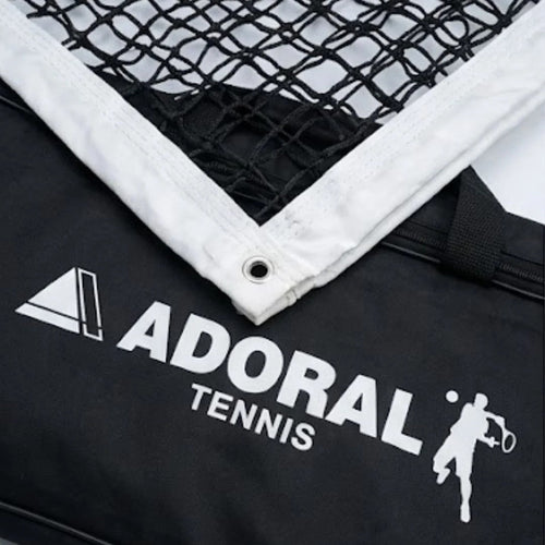 Adoral lawn tennis net double close-up showing black nylon mesh white tape border with metal eyelet and Adoral Tennis branding